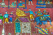 Wat Xieng Thong temple in Luang Prabang, Laos.  La Chapelle Rouge , the Red Chapel. The exterior walls are decorated with colourful mosaics on a pink background with scenes of people daily activities. South wall. 